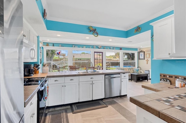 kitchen with stainless steel appliances, tile counters, sink, and white cabinets