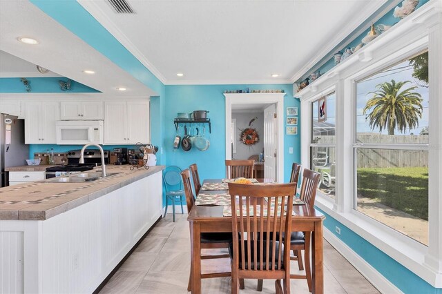 tiled dining room with sink and crown molding