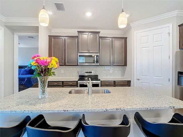 kitchen with decorative light fixtures, dark brown cabinets, ornamental molding, stainless steel appliances, and backsplash