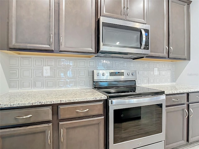 kitchen featuring stainless steel appliances, light stone counters, and tasteful backsplash