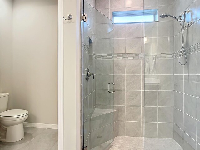 bathroom featuring tile patterned floors, toilet, and an enclosed shower