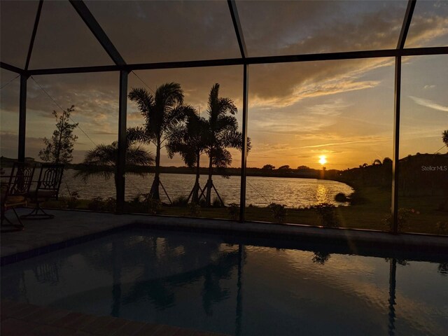 pool at dusk featuring a water view