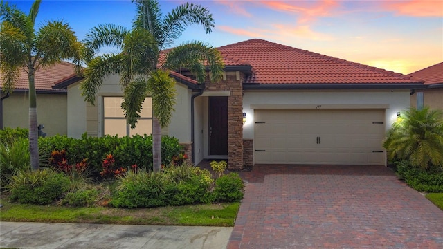 177 Vinadio Blvd, Nokomis, FL 34275 - mediterranean / spanish-style home with stucco siding, driveway, stone siding, a garage, and a tiled roof