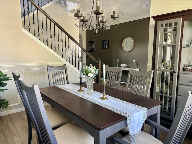 dining area featuring crown molding, a textured ceiling, wood-type flooring, and a notable chandelier