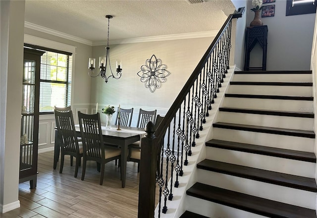 interior space with a textured ceiling, ornamental molding, and a chandelier