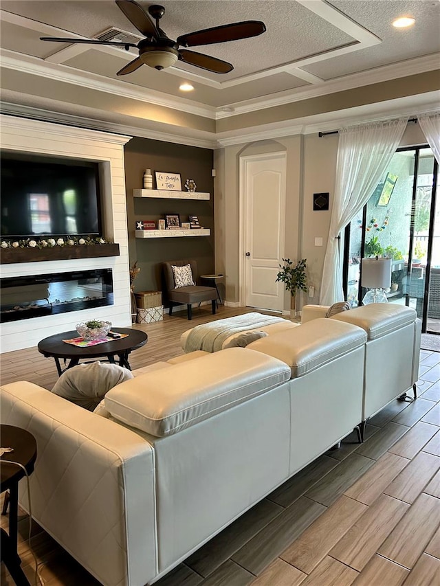 living room with a large fireplace, a textured ceiling, built in features, ceiling fan, and hardwood / wood-style flooring