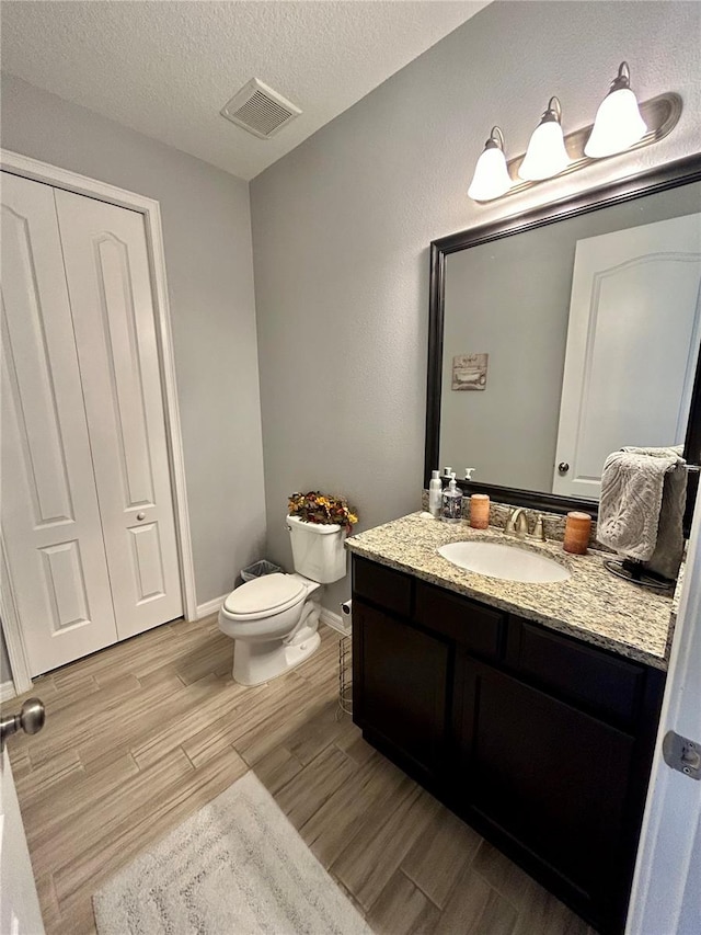 bathroom with toilet, a textured ceiling, and vanity