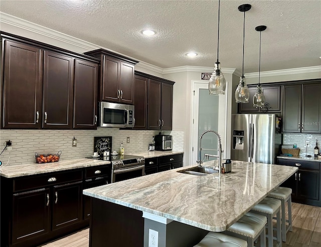 kitchen with backsplash, hanging light fixtures, appliances with stainless steel finishes, light hardwood / wood-style floors, and dark brown cabinetry