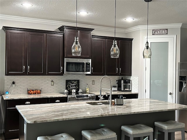 kitchen with light stone counters, stainless steel appliances, a center island with sink, and tasteful backsplash