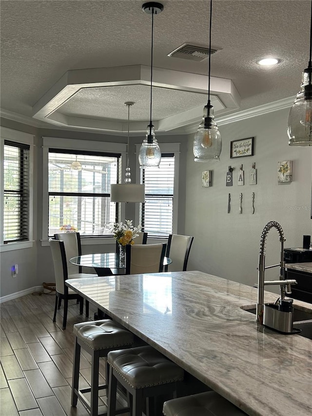 dining room with crown molding, a textured ceiling, hardwood / wood-style flooring, and sink