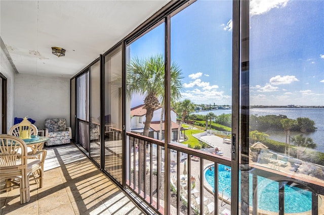 sunroom featuring a water view