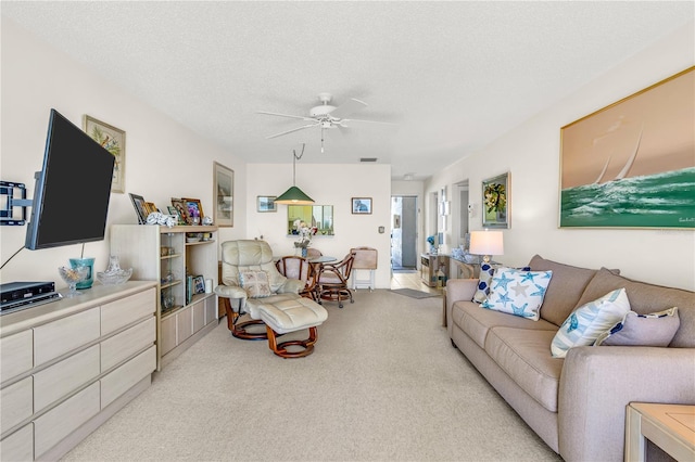 carpeted living room with a textured ceiling and ceiling fan