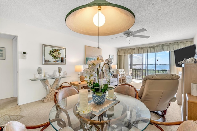 carpeted dining space with a textured ceiling and ceiling fan