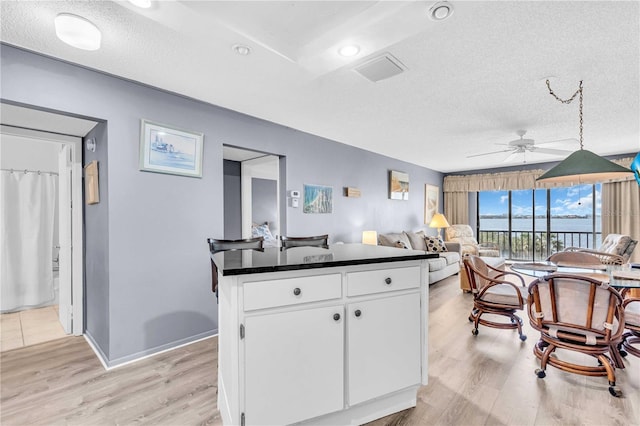 1602 Stickney Point Rd Unit 305, Sarasota, FL 34231 - kitchen with a ceiling fan, visible vents, dark countertops, light wood-type flooring, and white cabinets