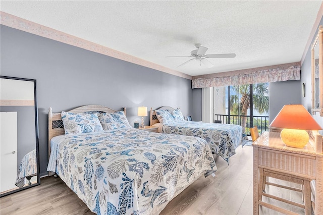1602 Stickney Point Rd Unit 305, Sarasota, FL 34231 - bedroom with access to outside, a textured ceiling, a ceiling fan, and wood finished floors