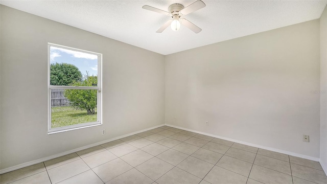 spare room featuring a textured ceiling, ceiling fan, a healthy amount of sunlight, and light tile patterned floors