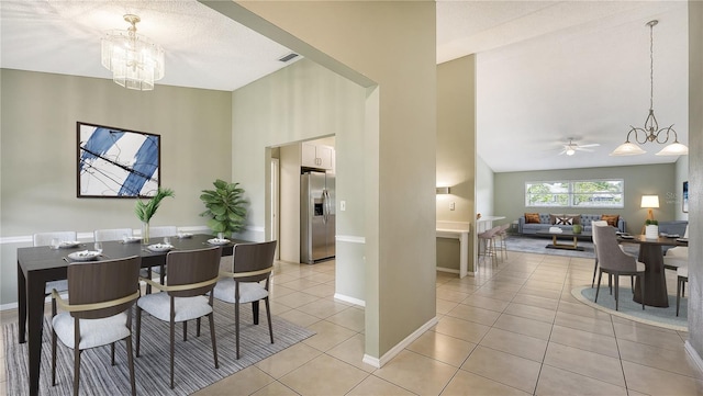 dining space featuring lofted ceiling, light tile patterned flooring, ceiling fan with notable chandelier, visible vents, and baseboards