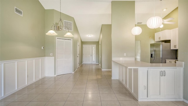 kitchen featuring light tile patterned floors, high vaulted ceiling, stainless steel fridge with ice dispenser, hanging light fixtures, and white cabinets