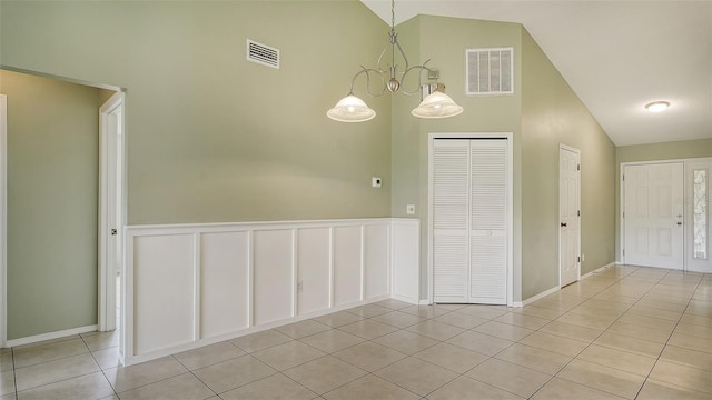 tiled empty room featuring high vaulted ceiling and a chandelier