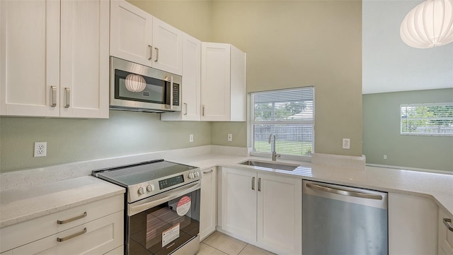 kitchen featuring white cabinetry, light stone countertops, light tile patterned floors, sink, and stainless steel appliances