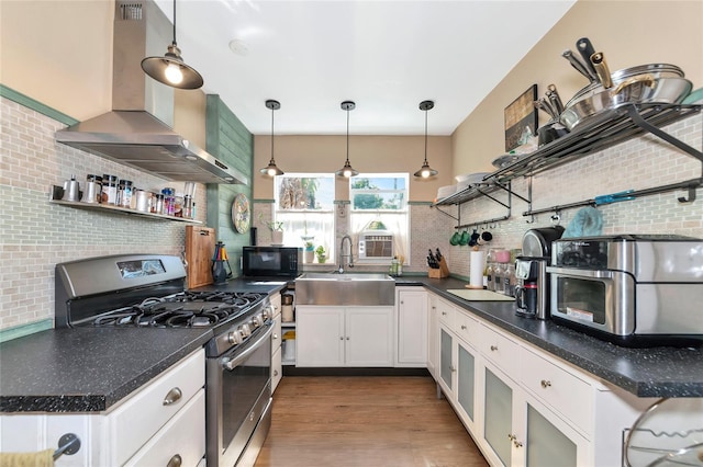 kitchen with sink, decorative light fixtures, stainless steel range with gas stovetop, island exhaust hood, and white cabinets