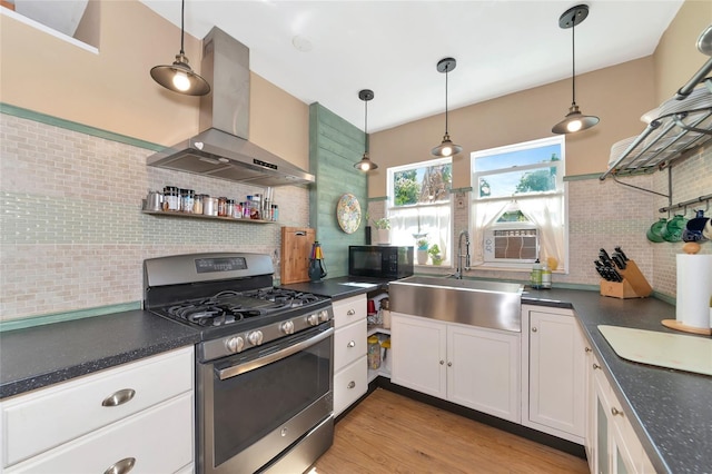 kitchen featuring sink, white cabinets, island exhaust hood, gas range, and decorative light fixtures