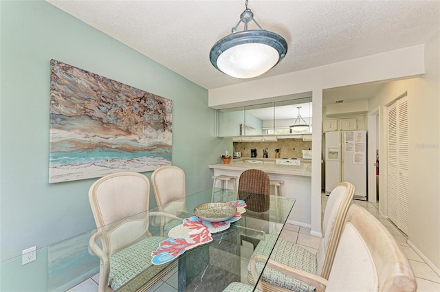 dining area with a textured ceiling and light tile patterned floors