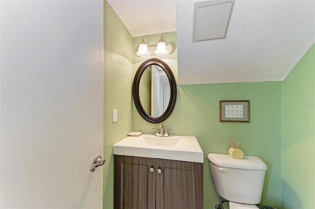 bathroom featuring lofted ceiling, a textured ceiling, toilet, and vanity