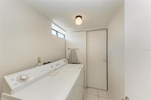 laundry room with washer and dryer, laundry area, light tile patterned flooring, and a textured ceiling