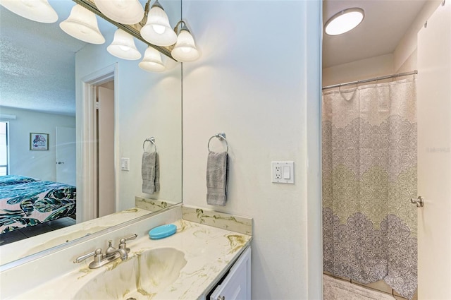 bathroom with connected bathroom, vanity, and a textured ceiling