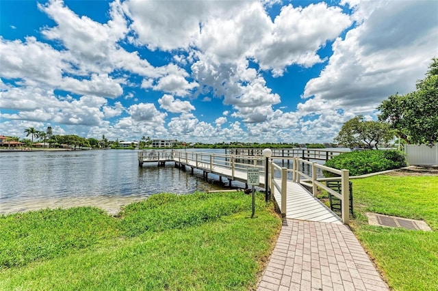 view of dock with a yard and a water view