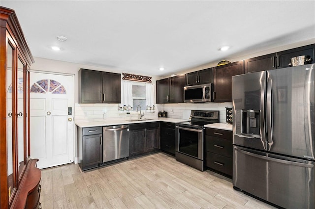 kitchen featuring sink, appliances with stainless steel finishes, tasteful backsplash, and light wood-type flooring