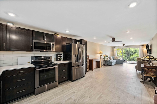 kitchen with appliances with stainless steel finishes, light wood-type flooring, ceiling fan, and backsplash