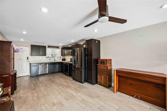 kitchen featuring appliances with stainless steel finishes, tasteful backsplash, sink, light wood-type flooring, and ceiling fan