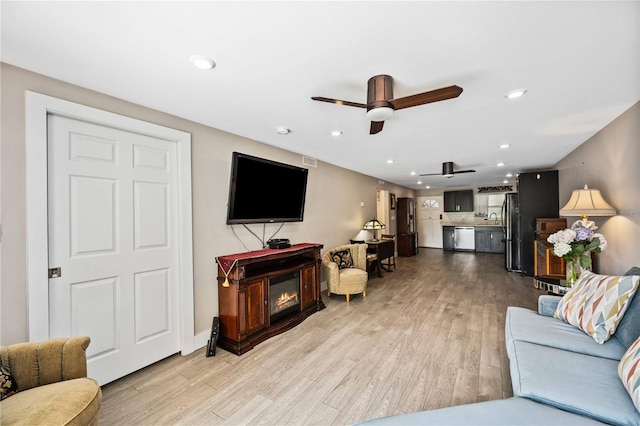 living room featuring light hardwood / wood-style flooring and ceiling fan