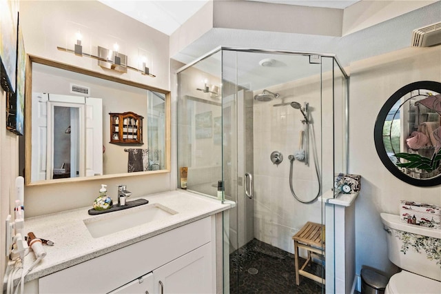 bathroom featuring a shower with shower door, vanity, and toilet