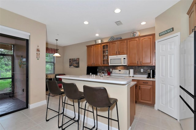 kitchen with light tile patterned flooring, tasteful backsplash, an island with sink, pendant lighting, and white appliances