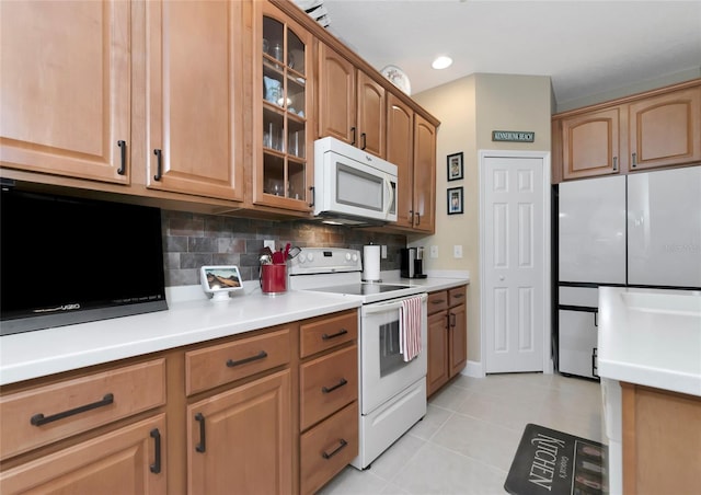 kitchen featuring light tile patterned flooring, white appliances, and tasteful backsplash