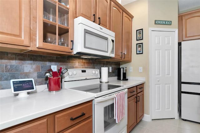 kitchen with light tile patterned floors, white appliances, and decorative backsplash