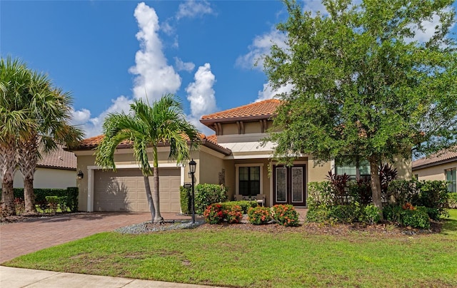 mediterranean / spanish home featuring a garage and a front yard