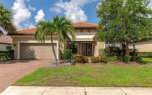 mediterranean / spanish-style house featuring a garage and a front lawn