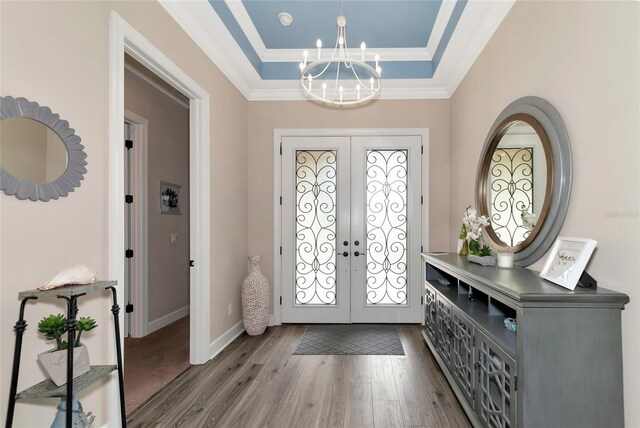 entrance foyer featuring a notable chandelier, crown molding, french doors, hardwood / wood-style floors, and a raised ceiling