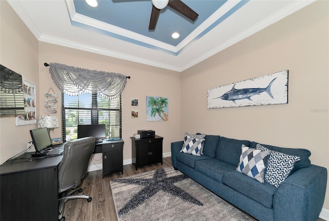 home office with ceiling fan, a tray ceiling, dark hardwood / wood-style flooring, and ornamental molding