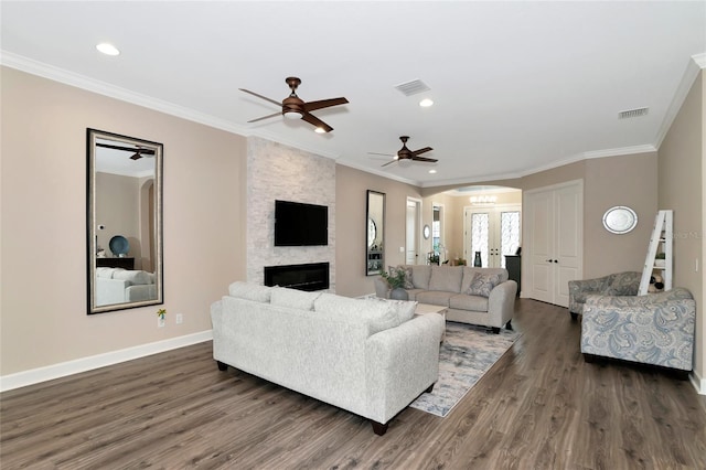 living room with dark hardwood / wood-style floors, a fireplace, ornamental molding, and ceiling fan