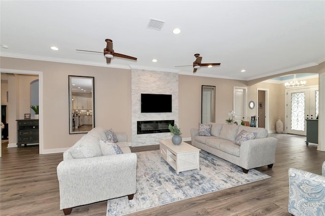 living room with ceiling fan with notable chandelier, hardwood / wood-style floors, a fireplace, and ornamental molding