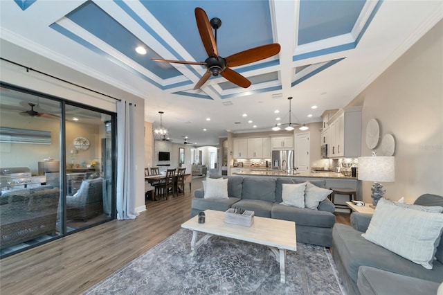 living room with ornamental molding, coffered ceiling, ceiling fan with notable chandelier, and light wood-type flooring