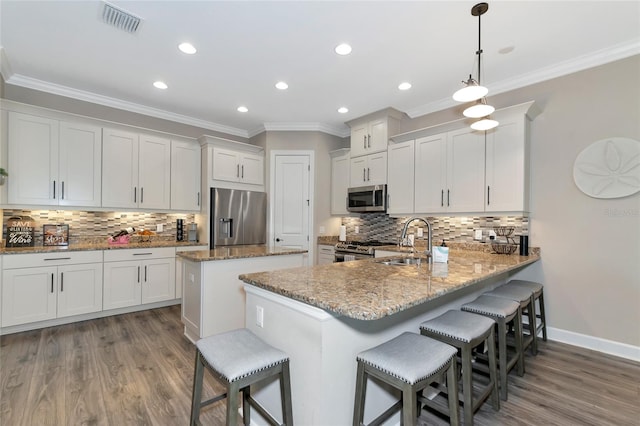 kitchen featuring stainless steel appliances, hardwood / wood-style floors, kitchen peninsula, decorative backsplash, and white cabinetry