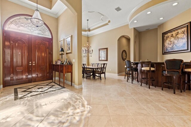 entrance foyer with ornamental molding, light tile patterned floors, and a tray ceiling