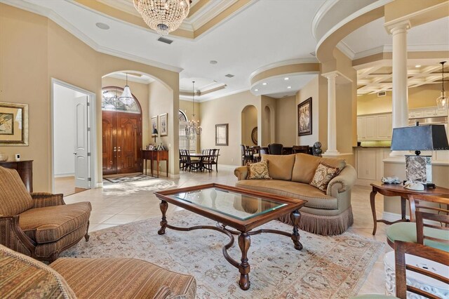 tiled living room with a tray ceiling, crown molding, ornate columns, and an inviting chandelier