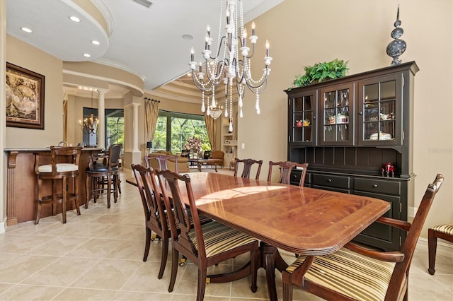 tiled dining space with decorative columns, crown molding, and a chandelier